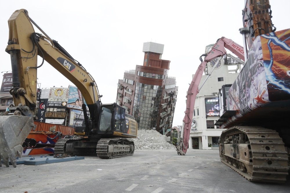 Earthquake aftershocks halt the demolition of a leaning building in Taiwan. Death toll rises to 13