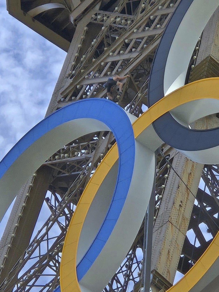 A man is seen climbing the Eiffel Tower, prompting an evacuation hours before closing ceremony